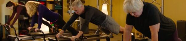 Pilates instructor assisting client on reformer equipment - private Pilates training
